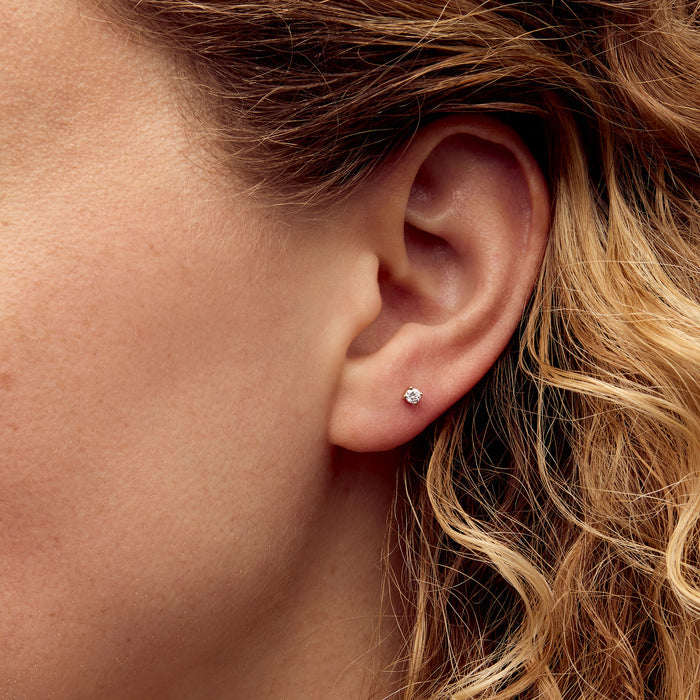 14kt yellow gold diamond stud earring with round stone on model’s ear