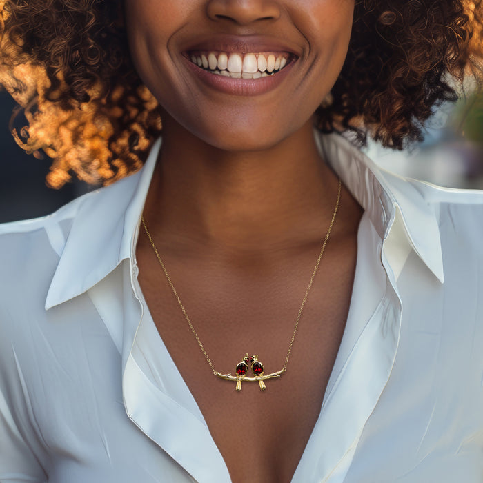Gold branch necklace with two red cardinal charms, worn over a white collared shirt