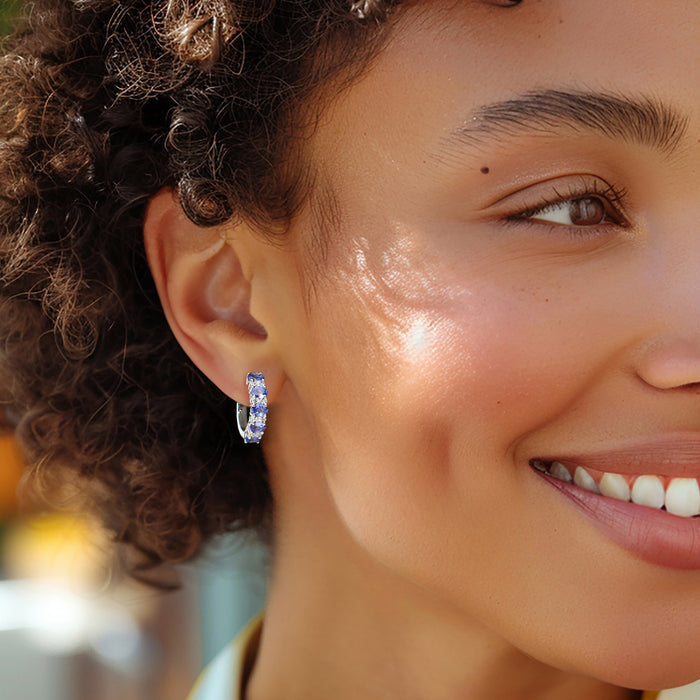 Sterling silver hoop earrings with purple tanzanite and clear topaz on ear