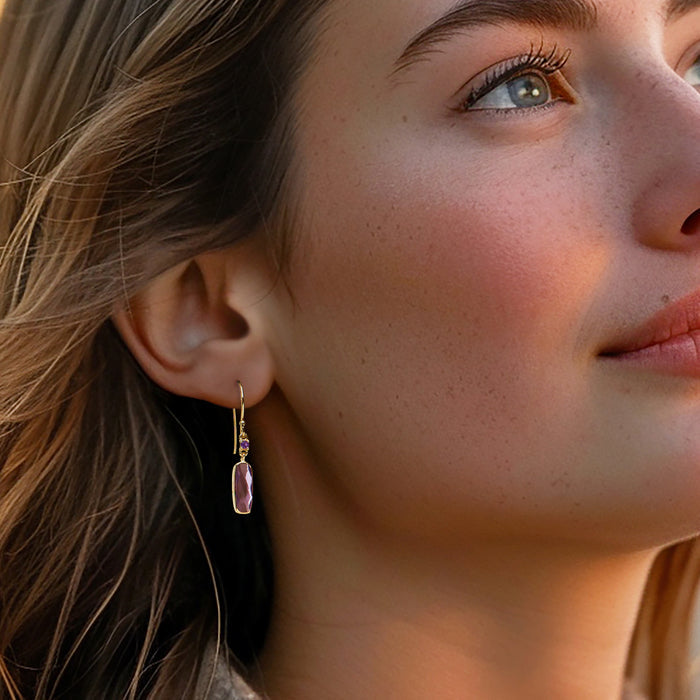 Amethyst drop earrings with purple oval stones and gold-tone earwire hooks, worn