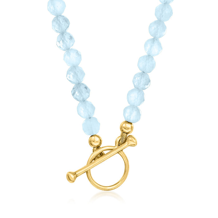 Aquamarine bead charm necklace with gold toggle clasp and bead strand tassel details.