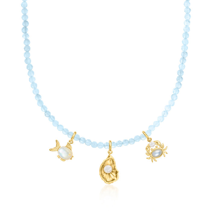 Aquamarine bead necklace with gold charm accents: bee, sun, and coin-like pendant.