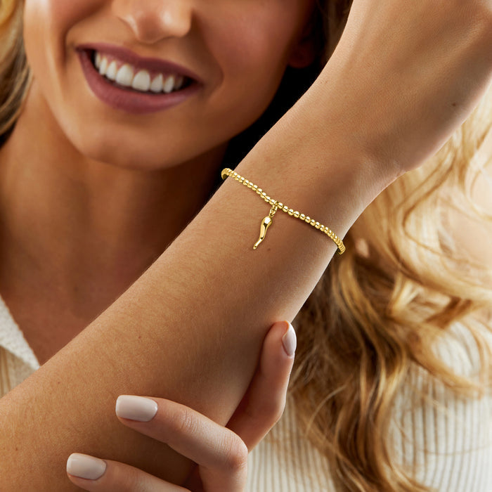 Gold bead stretch bracelet with tiny horn charm on wrist