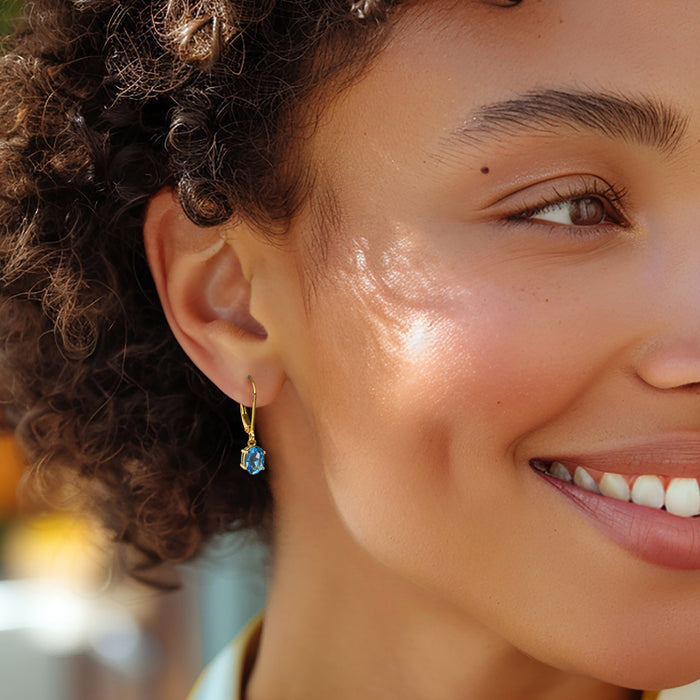 Gold-tone leverback drop earrings with blue faceted gemstone