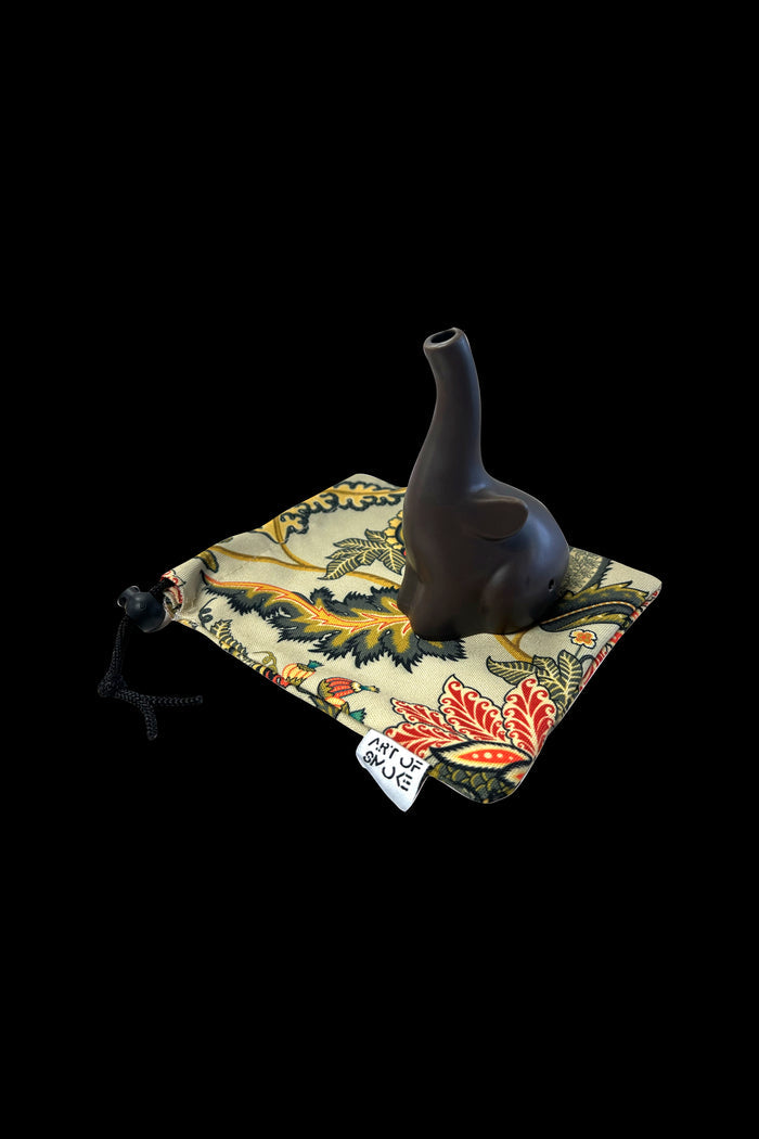 Dark brown oil lamp pipe rests inside a patterned drawstring bag with “Art of Smoke” printed on it.