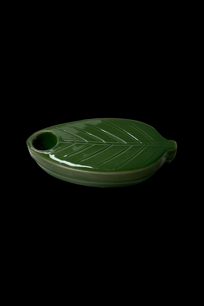 Green ceramic ashtray shaped like a cannabis leaf.