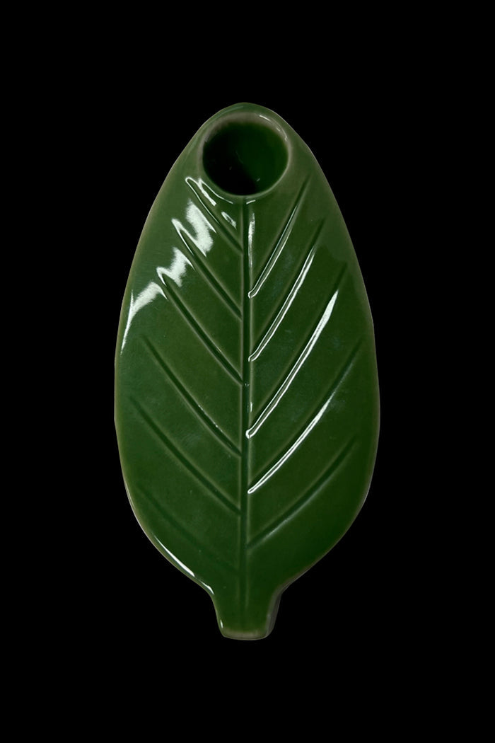 Green ceramic cannabis leaf pipe isolated on a black background.