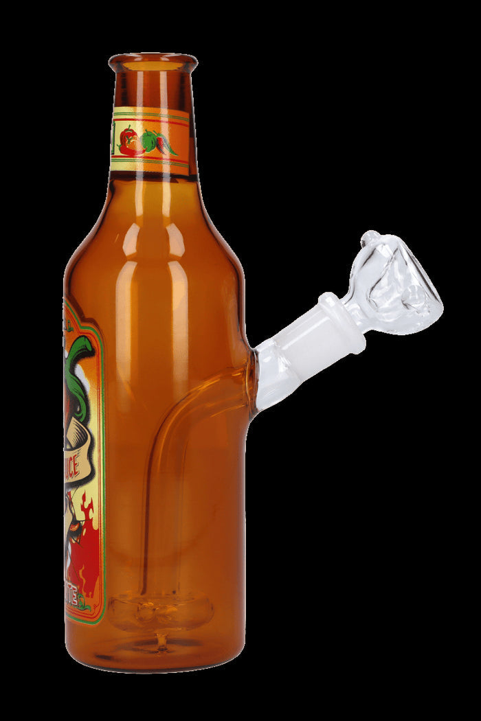 A glass water pipe shaped like a hot sauce bottle with a clear glass bowl.
