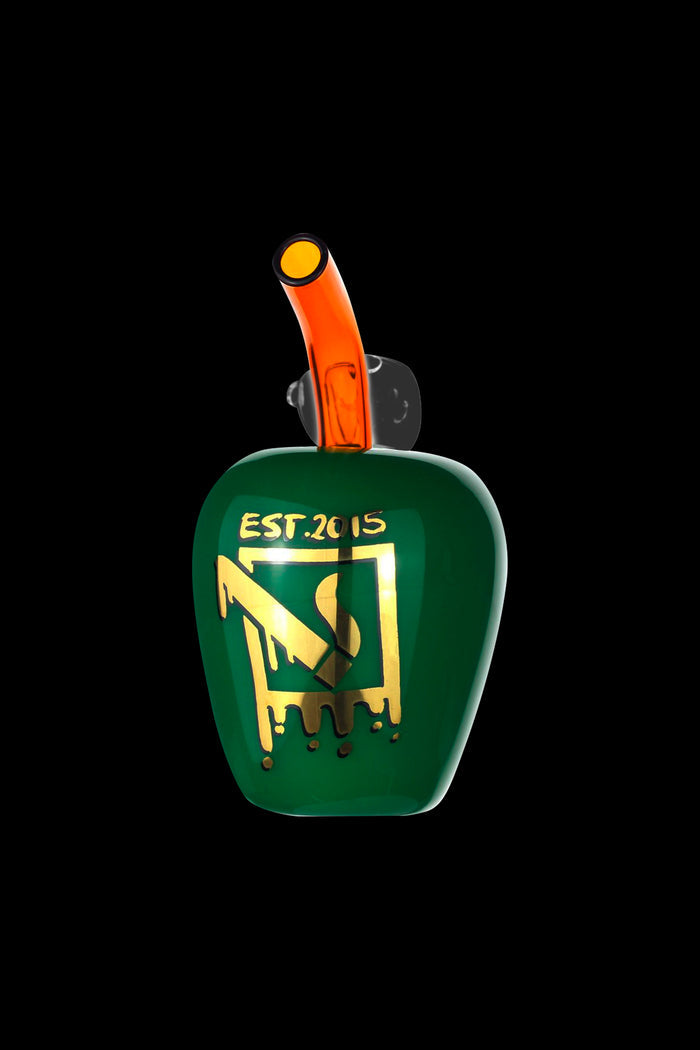 Green glass water pipe with gold lettering "EST. 2015" and dripping gold glaze, isolated on a black background.