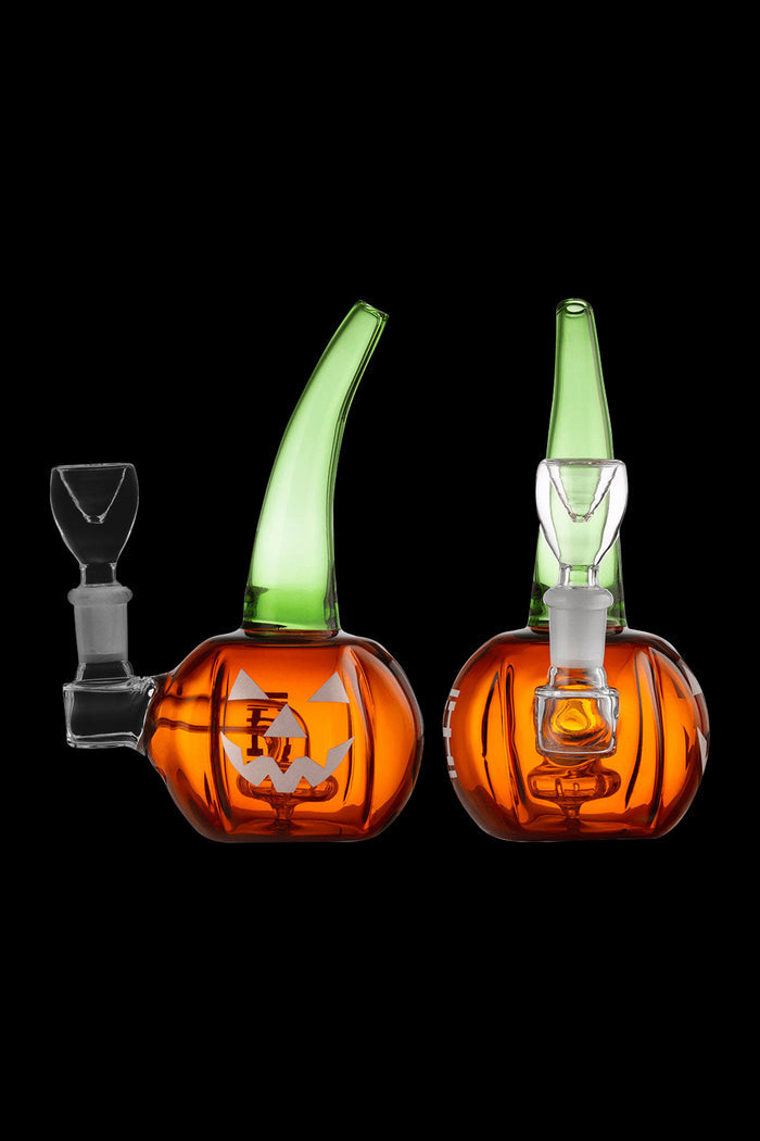 Two orange and green glass pumpkin-shaped dab rigs with clear glass attachments, isolated on a black background.
