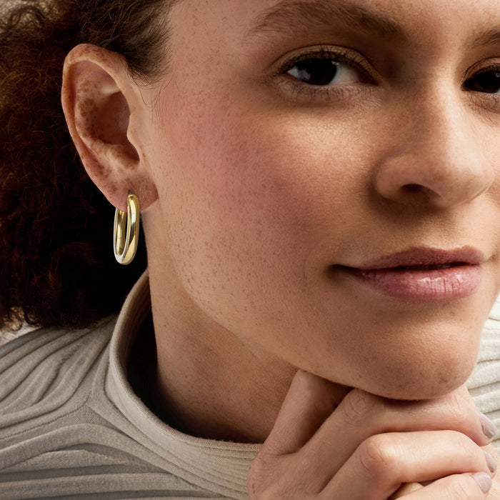 Gold oval hoop earrings worn, polished oval hoops on ear