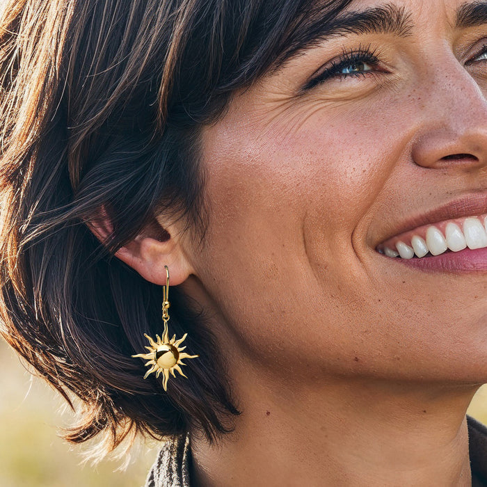 Gold sun dangle earrings on model, textured sun charms on earwire hooks