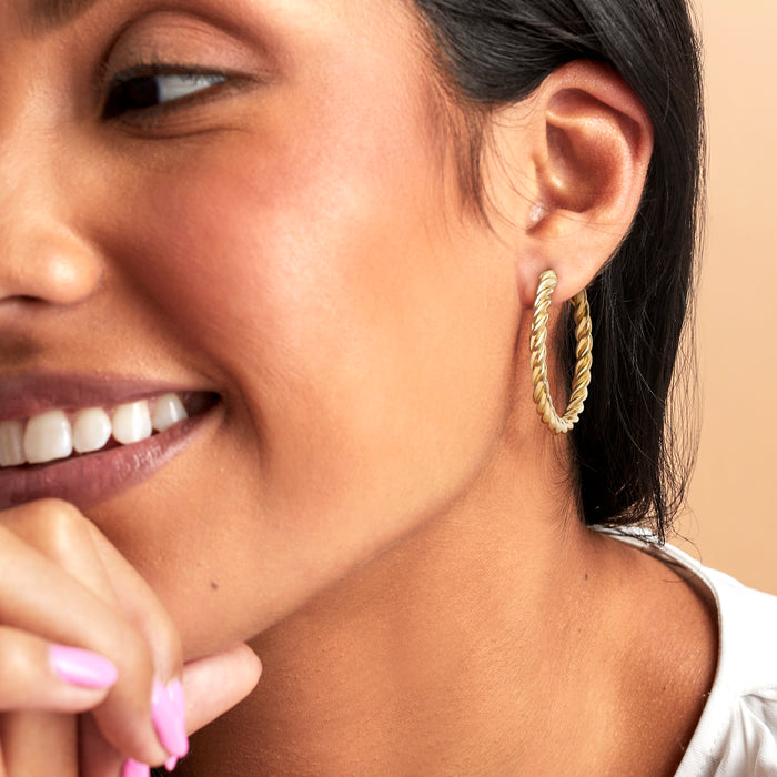 Gold twisted hoop earrings on model, twisted rope texture with hinged clasp