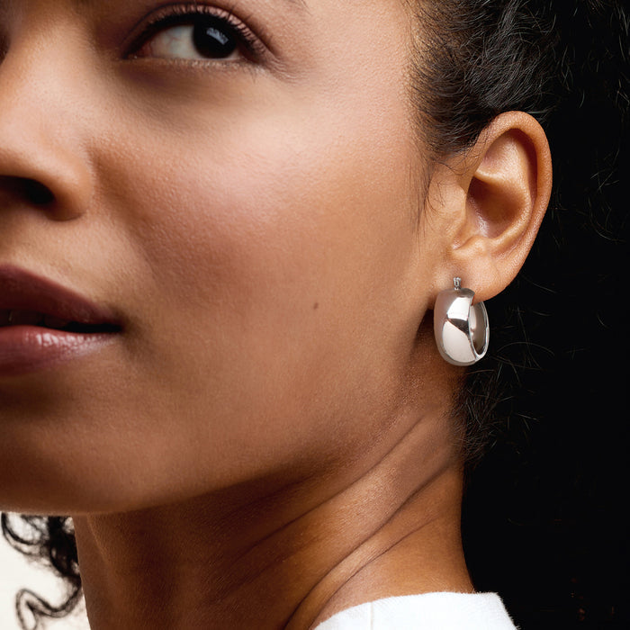 Sterling silver hoop earring worn on ear, polished oval round profile