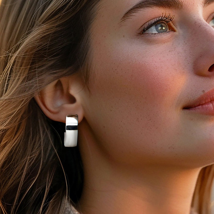 Oval hoop earrings in polished sterling silver, worn on the ear