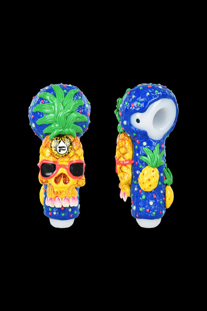 Colorful glass skull pipe decorated with tropical fruit and foliage, shown from two angles.