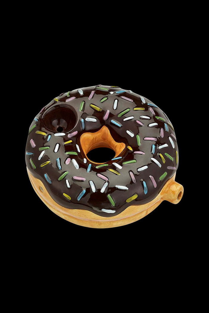 Chocolate donut-shaped glass pipe with colorful sprinkles, isolated on a black background."