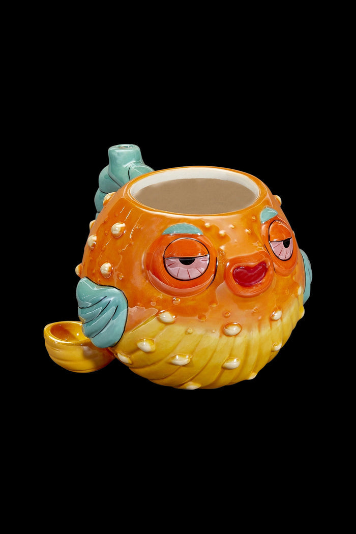 Orange pufferfish-shaped water pipe with closed eyes and a whimsical expression, isolated on a black background.